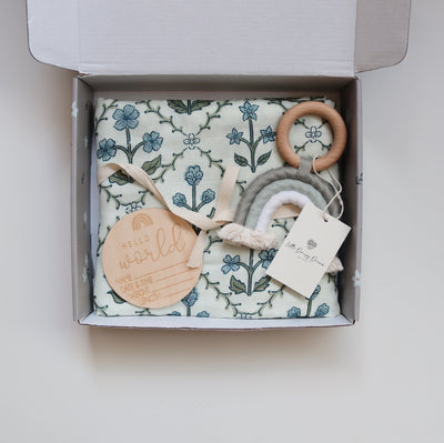 Blue botanical baby gift box with floral swaddle and milestone plaque
